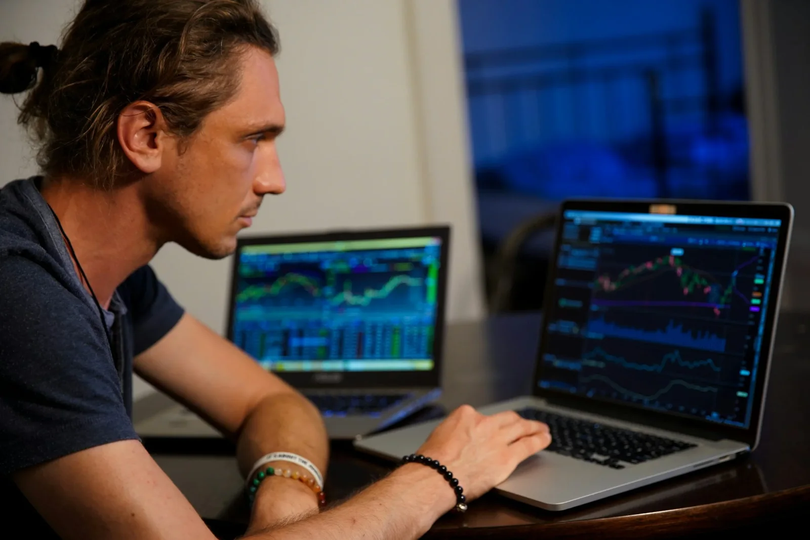 A trader studying market charts on two laptop screens